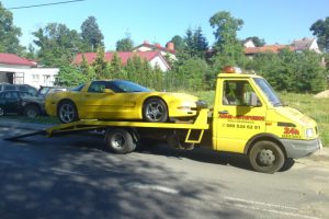 Żółta laweta z samochodem.