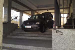 Czarny samochód zaparkowany na schodach budynku.