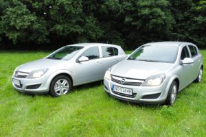 Dwa srebrne samochody zaparkowane na trawiastym polu.